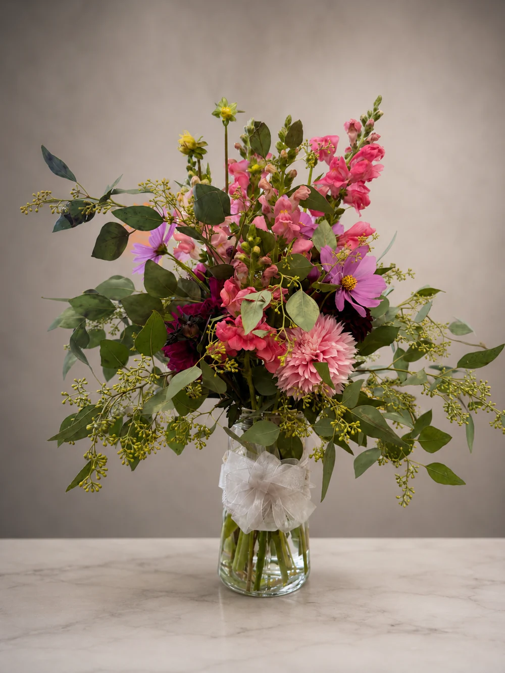 Loose garden arrangement of pink, purple, and burgundy flowers with airy greenery
