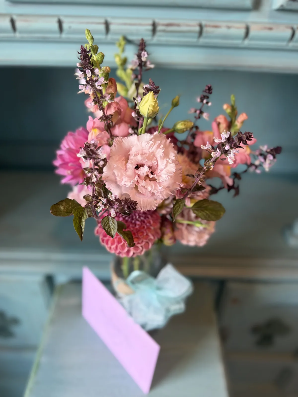 Petal-pink arrangement of lisianthus, dahlias, and snapdragons in a glass vase